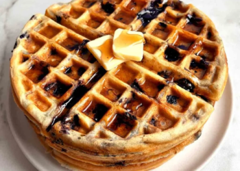 Golden brown blueberry waffles topped with fresh blueberries and syrup