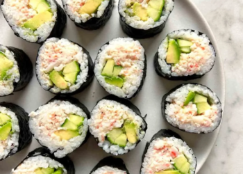 California Rolls with fresh ingredients and sushi rice on a wooden plate