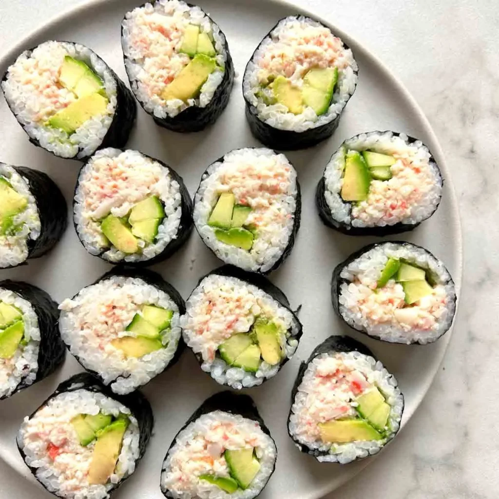 California Rolls with fresh ingredients and sushi rice on a wooden plate