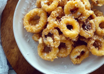 Plate of crispy salted egg calamari garnished with herbs and served with dips